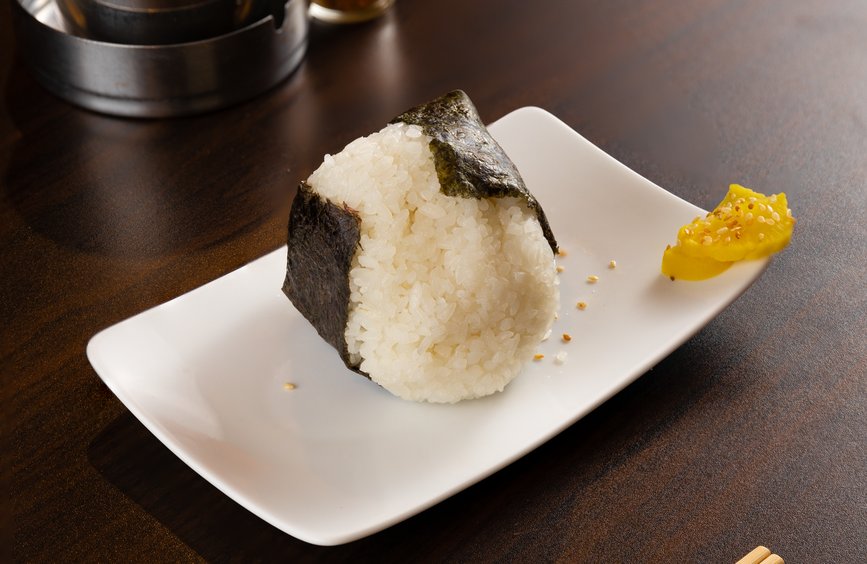 白い皿にのせた海苔巻きのおにぎり